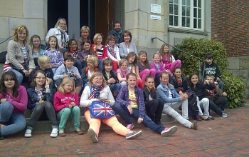 Zuerkennen ist ein Besuch aus Val de Reuil. Die Grundschule Ihlpohl sitzt mit französischen Gästen vor dem Eingang des Rathauses der Gemeinde Ritterhude.