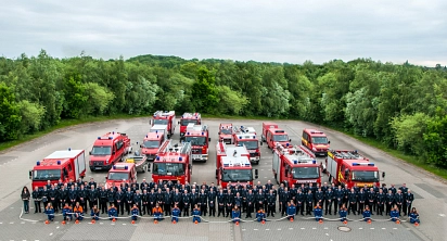 Zuerkennen sind 15 Feuerwehrautos mit dem ganzen Feuerwehrpersonal davorstehend, aus der Vogelperspektive mit vielen Bäumen im Hintergrund&nbsp;&copy;&nbsp;Feuerwehr Ritterhude
