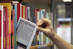 Das Foto zeigt ein Bücherregal. Zwischen den analogen Büchern befindet sich ein E-Book-Reader.&nbsp;&copy;&nbsp;Stadtbibliothek Nordhorn