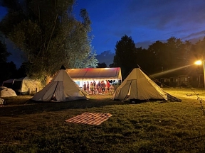 Dämmerung auf einem Campingplatz mit 2 beigen Zelten. Im Hintergrund sind Jugendliche unter einem Pavillon zu sehen.&nbsp;&copy;&nbsp;Gemeinde Ritterhude