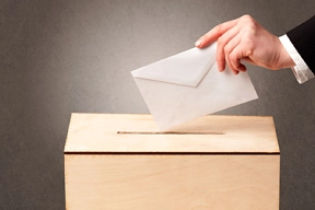 Zuerkennen ist eine menschliche Hand, die einen Briefumschlag in eine Wahlurne legt.&nbsp;&copy;&nbsp;ra2studio - Fotolia.com